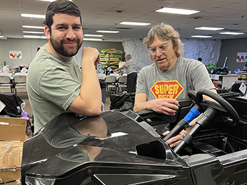 Two volunteers standing with one of our news cars