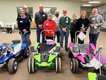 Several Rotary Club members standing behind some Geeks for Kids cars