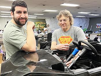 Two Geeks for Kids volunteers working on a car
