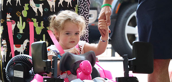 Young girl in Geeks car holding hands with parent